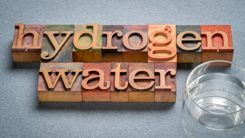 wooden blocks spelling out hydrogen water with glass of water